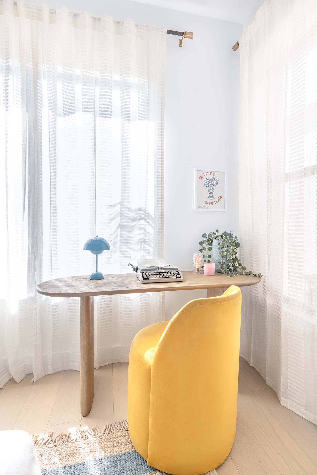 A quiet writing desk with a vintage typewriter and sheer curtains